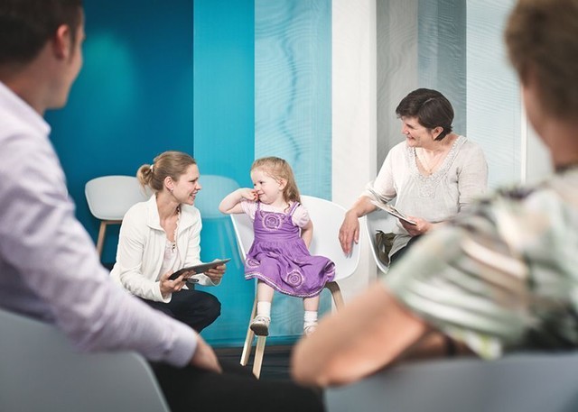 Image-Bild der medneo GmbH auf dem ein Wartezimmer mit Patienten abgebildet ist. Medizinisches Personal spricht mit einem Kind.