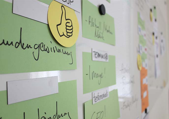 Nahaufnahme von Post-its an einem Whiteboard.